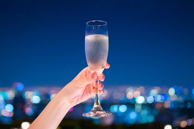 A hand holding champagne glass with beautiful bokeh at night