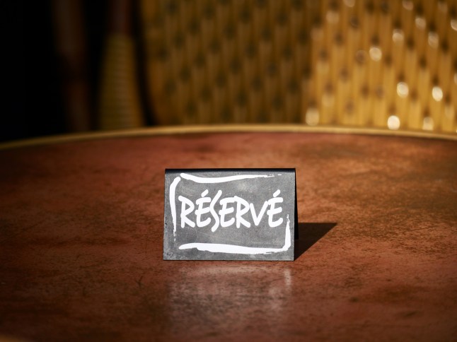 A metal easel placed on a table announces that it is reserved in Paris, France