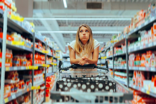Woman confused in a supermarket, leaning on trolley