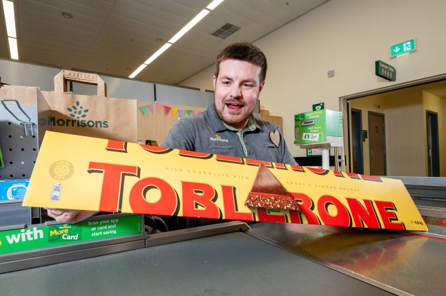 A Morrisons employee holding the giant Toblerone at the checkouts